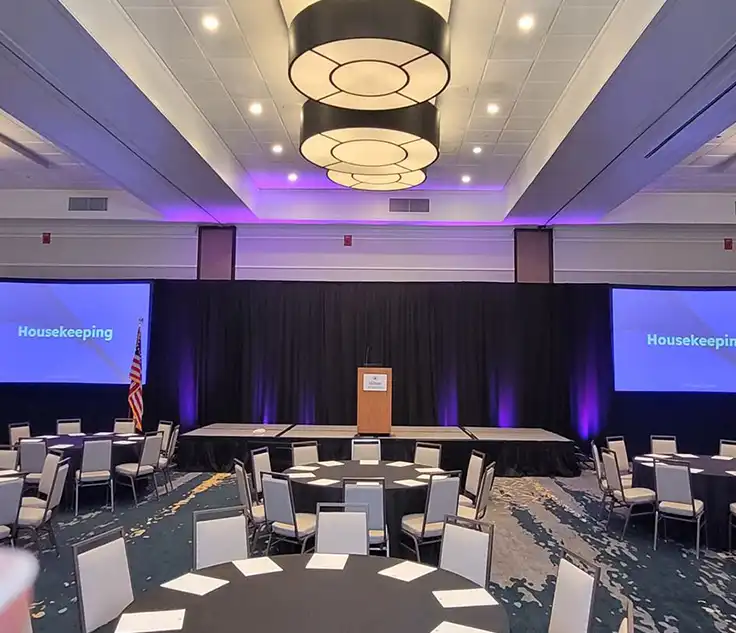 Affordable AV equipment setup in Atlanta conference room with dual projection screens, stage lighting, and round table seating